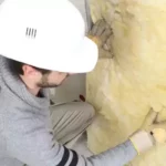 Строитель набивает минвату в стену